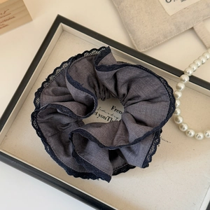 Detail of dark gray scrunchie with black lace trim and pearl accessories in background