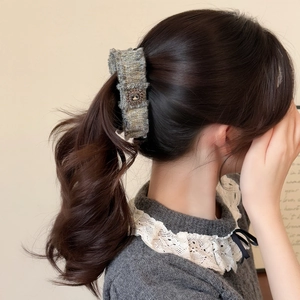 Dettaglio di un fermaglio per capelli in tweed con fibbia in metallo su una coda di cavallo