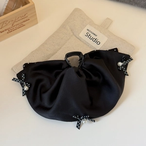 Detail von schwarzer Satin-Haarklammer mit weißen Punkten und elegantem Perlenanhänger