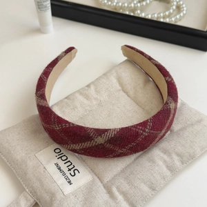 Detail of burgundy plaid fabric headband with thick wool texture for autumn winter