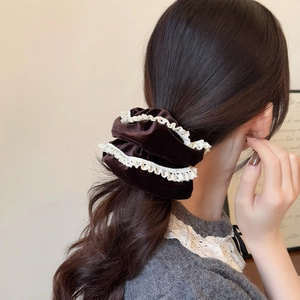 Close-up of velvet scrunchie with white lace trim on model ponytail