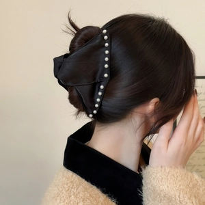 Detailed view of large black satin hair claw with white pearls on elegant updo hair