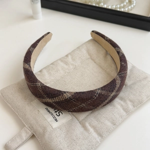 Detailed close-up of brown plaid fabric headband on a soft beige quilted pouch