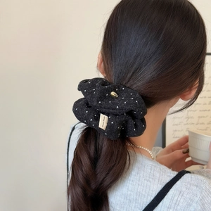 Detail of black polka dot velvet scrunchie with handmade label and gold pendant