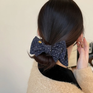 British style navy blue polka dot bow hair clip with gold logo on bun hairstyle