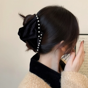Detail of vintage French black velvet bow hair claw with elegant pearl accents for women