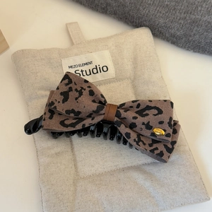 Détail du clip banane avec nœud imprimé léopard et étiquette métallique dorée Hand Made