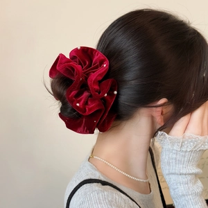 Detail of a burgundy velvet scrunchie with white pearls worn on a bun hairstyle