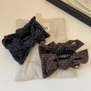 Polka dot bow hair claws in navy and brown fabric on a beige canvas pouch