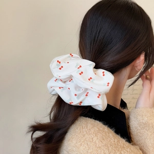 Elegante elastico bianco con stampa a ciliegie rosse indossato su una coda
