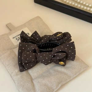 Detailed view of British style polka dot bow hair claw with gold label and fabric texture