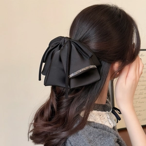 Elegant black satin bow hair clip with decorative pearls for a minimalist woman's hairstyle