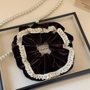 Detail of coffee velvet scrunchie with white lace trim on a decorative tray