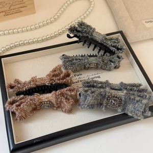 Dettaglio di fermagli per capelli a fiocco in tweed con strass quadrati su vassoio