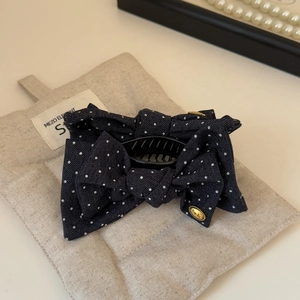 Close-up of British style navy polka dot bow hair claw clip with gold metal emblem