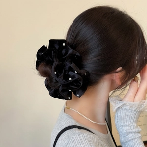Detail of a large black velvet scrunchie with white pearls on a model ponytail
