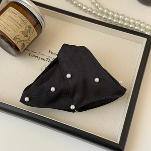 Close-up of elegant black fabric triangle hair claw with white pearls and French retro style