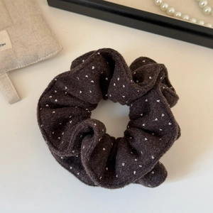 Detailed texture of charcoal grey velvet scrunchie with white heart pattern and soft fabric