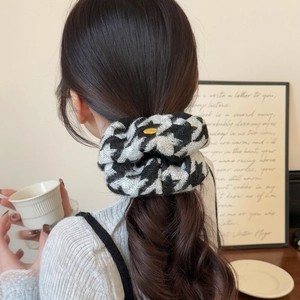 Black and white houndstooth knit hair scrunchie with gold medal on a ponytail