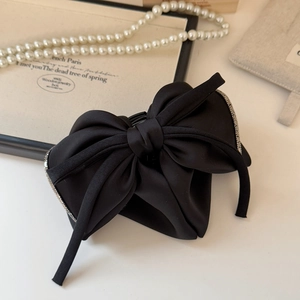 Detail view of premium black satin bow hair claw with elegant rhinestone trim edges