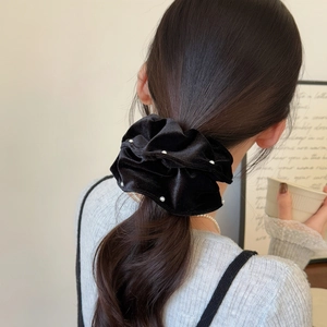 Detail of black velvet scrunchie with white pearls styled in a low ponytail hairstyle