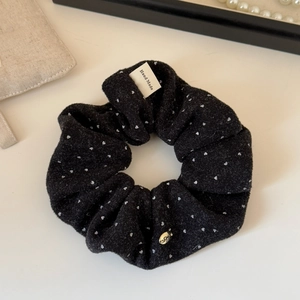 Close-up of black polka dot velvet scrunchie with Hand Made label and gold pendant charm