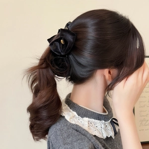 Detail of elegant black velvet bow hair claw clip with golden metal buckle on model