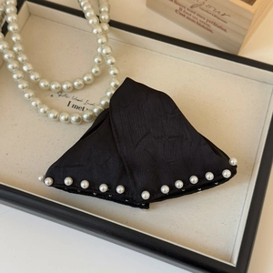 Detail of a black satin triangle hair claw clip with elegant white pearl accents