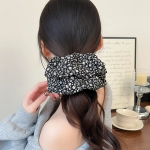 Elegant black floral fabric scrunchie for women shown on a low ponytail hair styling