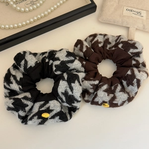 Detail of houndstooth knit hair scrunchies with elegant gold metal tags and plush texture