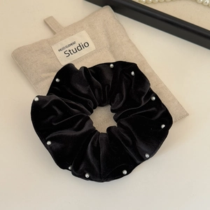 Detailed shot of black velvet scrunchie with white pearls and premium storage pouch