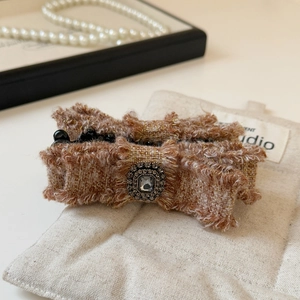 Dettaglio molletta per capelli a fiocco in tweed con cristallo quadrato e fili dorati