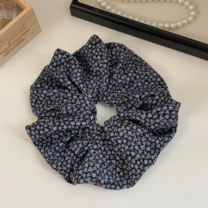 Detail of a navy blue floral chiffon scrunchie with a pearl necklace background