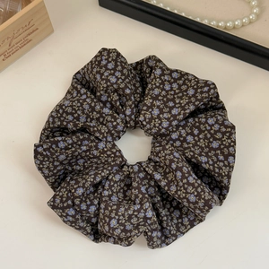 Detail of coffee-colored floral scrunchie with blue flower pattern on light background