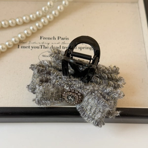 Dettaglio della pinza per capelli in tweed con strass grigio e bordi in filo dorato