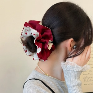 Polka dot and burgundy red satin scrunchie shown in a stylish hairstyle bun