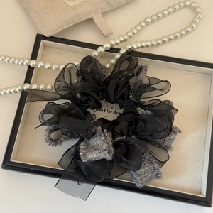 Detail of layered black organza and tweed scrunchie with an elegant bow design