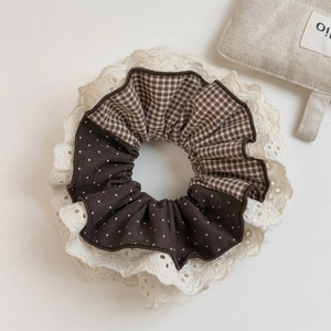 Dettaglio di scrunchie in pizzo a scacchi con pois marroni e texture di ricamo