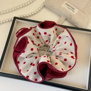 Close-up of fluffy red polka dot scrunchie with layered fabric on a decorative tray
