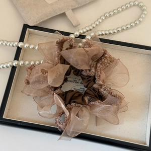 Close-up of brown organza scrunchie with gold wire edges on a jewelry display tray