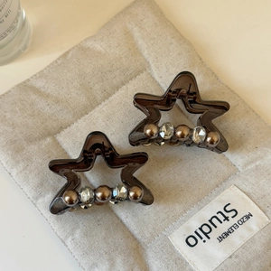 Detailed macro view of two star-shaped hair claws with resin finish and inlaid pearls