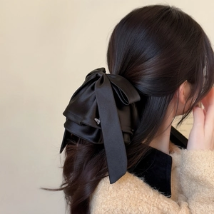 Detail of elegant black satin multi-layer bow hair clip with butterfly pendant on model