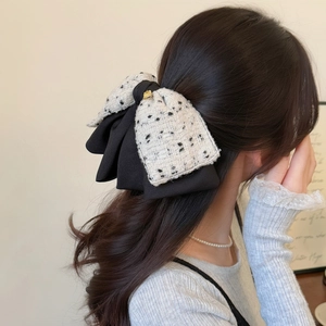 Detailed macro view of an elegant black and white tweed bow hair clip on model