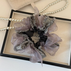 Detail of layered tulle and tweed scrunchie with bow design in purple and black