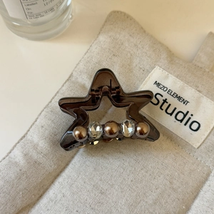 Detailed close-up of amber star hair claw clip with brown pearls and rhinestones