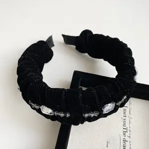 Close-up of elegant pleated black velvet headband with sparkling crystal rhinestones