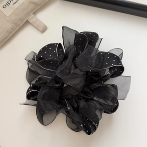 Detail of black mesh scrunchie with white polka dots featuring layered ruffle textures