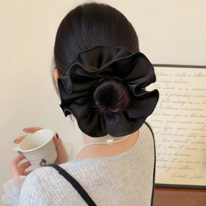Detail of large black satin scrunchie with soft silk luster on an elegant bun hairstyle