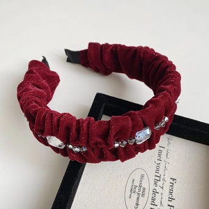 Detailed side view of wine red velvet pleated headband with crystal and bead embellishments