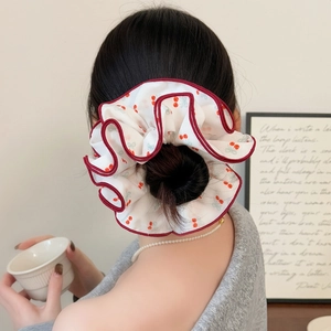 Chouchou élégant avec imprimé cerise et bord rouge présenté sur un chignon stylé